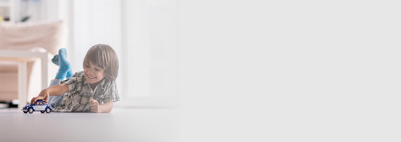 Një djalë që luan me një makinë lodër në dysheme.